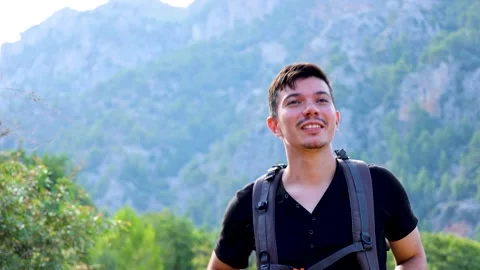 Close up of man walking happily with green mountains in the background Stock Footage 293569085