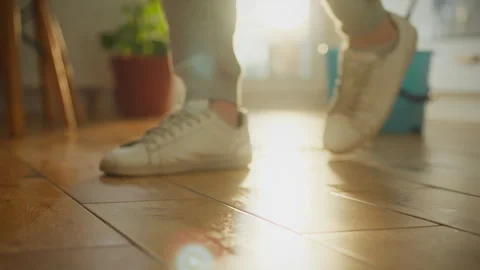 Close-up of a man walking with his feet in white sneakers on a wooden floor Stock Footage 331288864