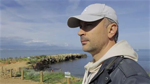 Close up of a man walking on a sandy footpath bordered by wooden posts connected Stock Footage 308782054
