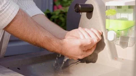 Close-up of a man washing his hands with water at an outdoor portable sink stati Stock Footage 336724007