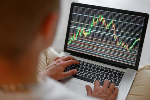 Close-up of a man watching a data index chart on a monitor. Stock Photos