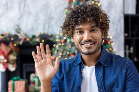 Close-up man waving at web camera, smiling and happy greeting, hispanic man on Stock Photos
