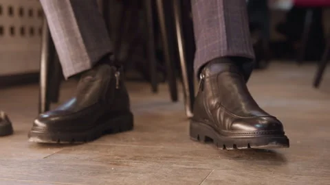 Close up of man wearing black leather boots with side zippers and gray plaid Stock Footage 345732604
