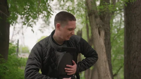 Close up of man wearing black quilted jacket adjusting protective vest in Stock Footage 345082392