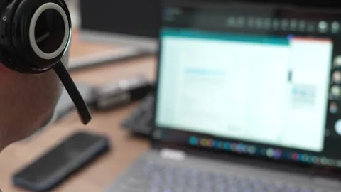 Close-up of a man wearing a headset while working on a laptop, likely in a .. Stock Footage 321285393
