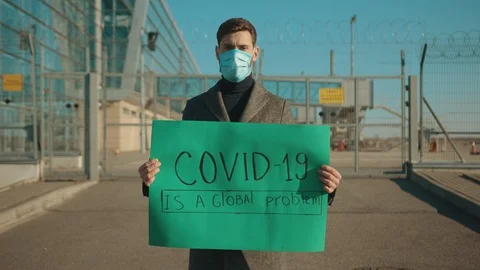 Close up man wearing protective mask on street hold poster COVID-19 is a global Stock Footage 126583825