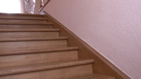 Close-up a man in white pants walking down the wooden step to first floor in Vídeo Stock 104087606