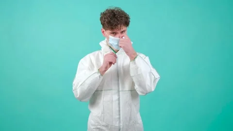 Close up of a man who wears protective suit and medical mask, looking at camera. Video stock 151546910