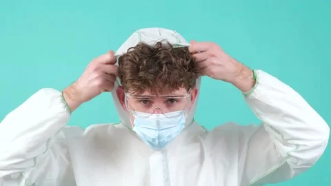 Close up of a man who wears protective suit and medical mask, looking at camera. Video stock 152727178