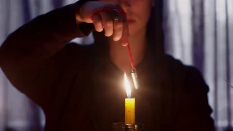Close up of man wizard rotating a magic pendulum over a candle Stock Footage 140829616