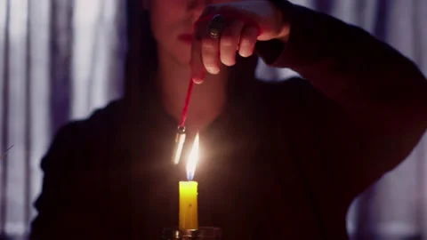 Close up of man wizard rotating a magic pendulum over a candle Stock Footage 179407706