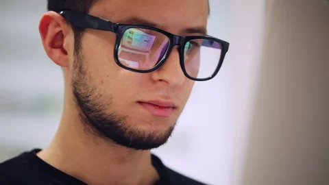 Close-up of a man working on a computer, reflection a screen with glasses Stock Footage 97387031