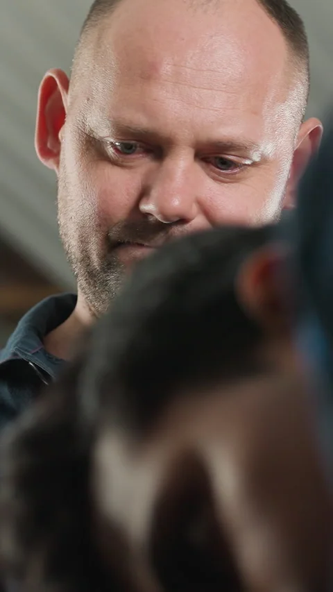 Close-Up of Man Working on Engine with Colleague Using Phone for Guidance Stock Footage 318199343