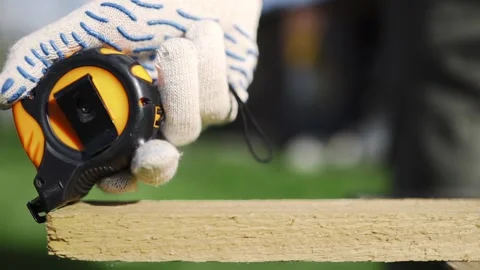 Close up of man in working gloves measuring wooden block by roulette before Stock Footage 89467467