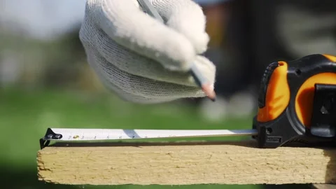 Close up of man in working gloves measuring wooden block by roulette and marks Stock Footage 89494623