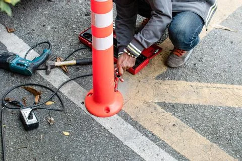 Close up a man is working by installing a small traffic cone on the road, a.. Stock Photos