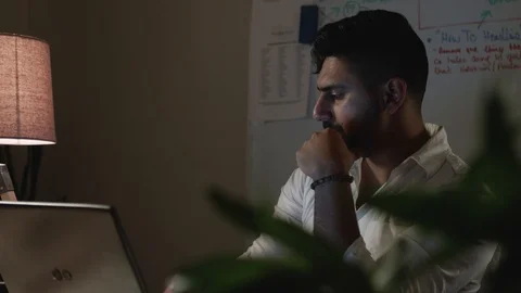 Close Up Man Works Back Late in Dark Office at Night, Takes Notes at Desk Stock Footage 108892309