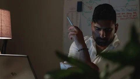 Close Up Man Works Back Late in Dark Office at Night, Takes Notes at Desk Stock Footage 108892434