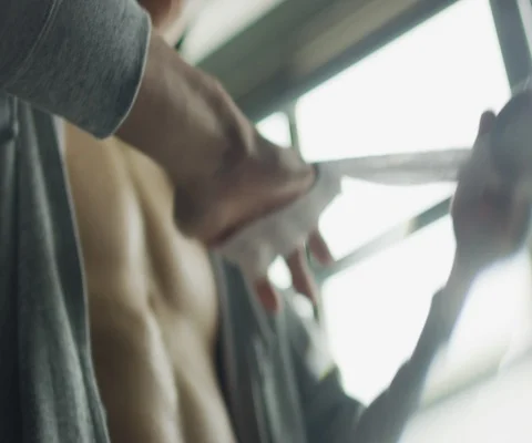 Close up of man wrapping up his hand with bandage in gym Video stock 147046013