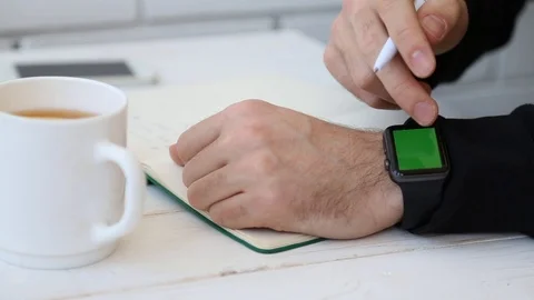 Close Up of Man Writing in Notebook and Touches Screen Of Smart Watch. Stock Footage 116613828
