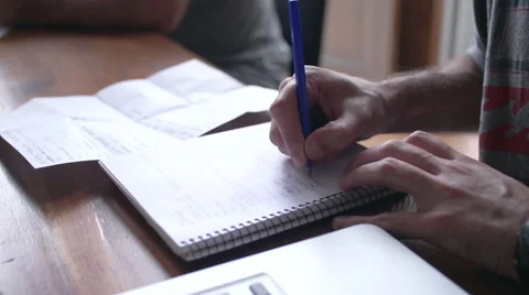 Close-up of man writing in notebook with laptop computer nearby Stock Footage 63303593