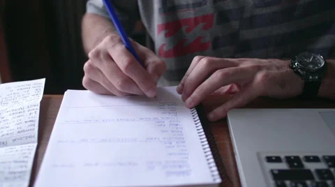 Close-up of man writing in notebook with laptop computer nearby Stock Footage 63303605