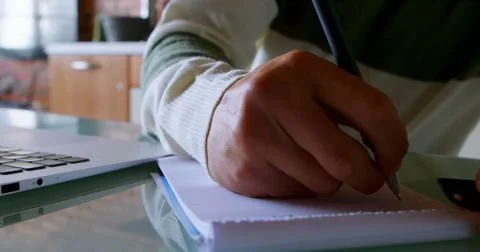 Close-up of man writing on notepad on table at home 4k Foto stock