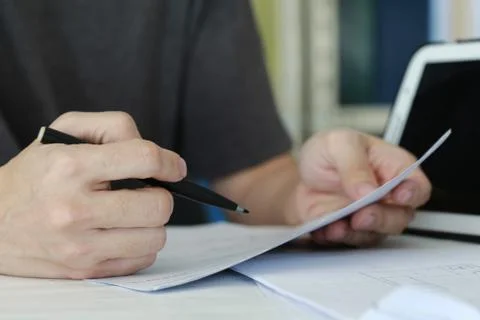 Close up man Writing on Paper on the Table in a office room. mobile device pl Stock Photos
