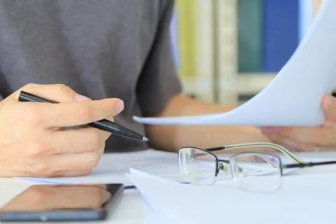 Close up man Writing on Paper on the Table in a office room. mobile device pl Stock Photos
