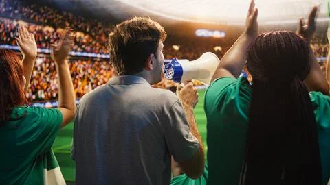 Close up of man yelling through megaphone in soccer stadium to cheer players Stock-Fotos