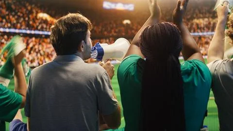 Close up of man yelling through megaphone in soccer stadium to cheer players Stock-Fotos