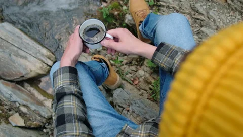 Close up of man in yellow beanie while drinking coffee, sitting near lake Stock-Footage 198829905