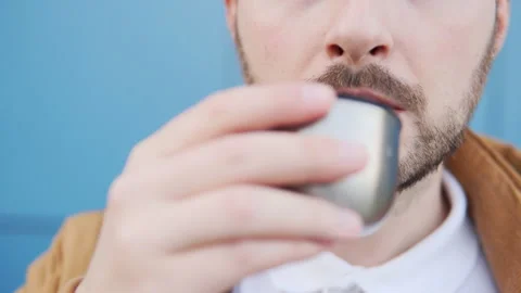 A close-up of a man in a yellow jacket and white polo drinks a hot tea or coffee Stock Footage 135421227