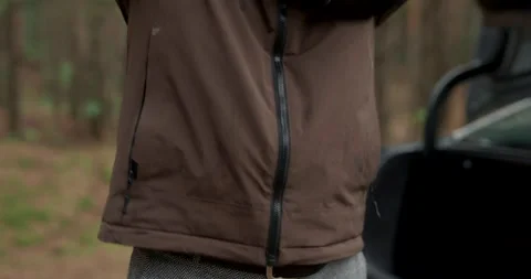 Close up of man zipping up waterproof jacket in rainy forest with audio included Stock Footage 340843566
