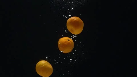 Close-up of mandarins falling down into the water against a black background. Stock-Footage 272599578