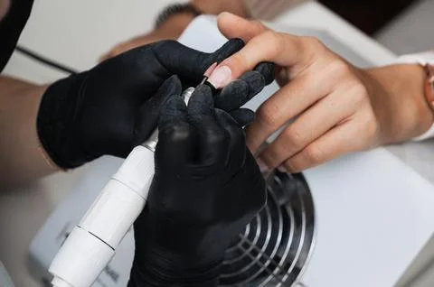 A close-up of a manicure master processing the nail surface with a cutter on an Stock Photos
