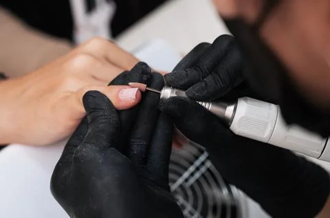 A close-up of a manicure master processing the nail surface with a cutter on an Stock Photos