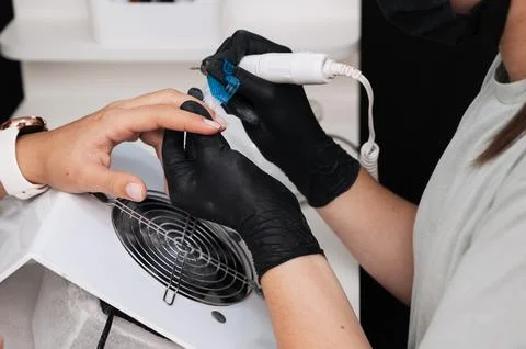 Close-up of the manicure master sawing the surface of the nail with a cutter on Stock Photos