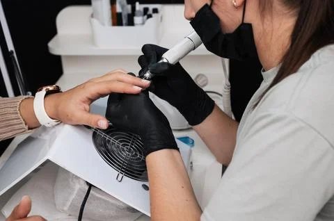 Close-up of the manicure master sawing the surface of the nail with a cutter on Stock Photos