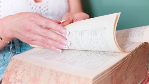 Close-Up of Manicured Hand Gently Turning Book Pages, 4K Stock Footage 273181875