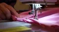 Close up manicured old woman hands sew together pleats of pink fabric HD Footage