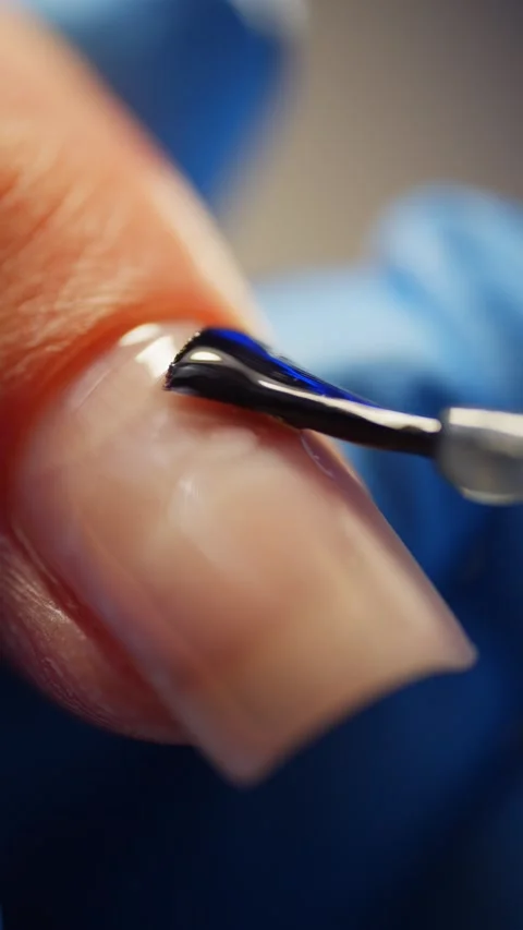 Close-up of a manicurist applying gel base coat to a nail. Stock Footage 314797523