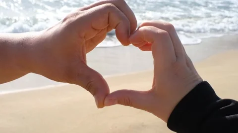 A close-up of a mans and womans hand in the shape of heart against the Stock Footage 317537375