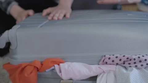 Close-up of man's and woman's hands trying to pack a suitcase before travel Stock Footage 108737798