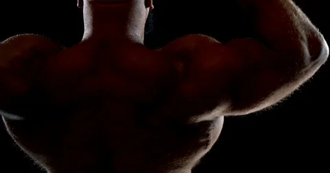Close-up of a man's back and shoulders with bronze skin on a black background Stock Footage 124707010