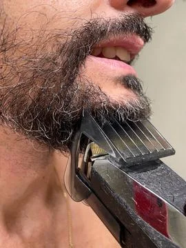 Close-up of a man's beard while shaving with an electric razor Stock Photos