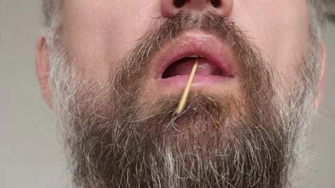 Close up of man's bearded face chewing toothpick Stock Footage 134948410
