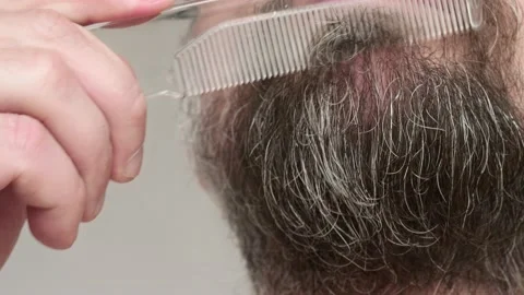 Close up of man's bearded face. Man brushes his beard with hairbursh. Stock Footage 134954747