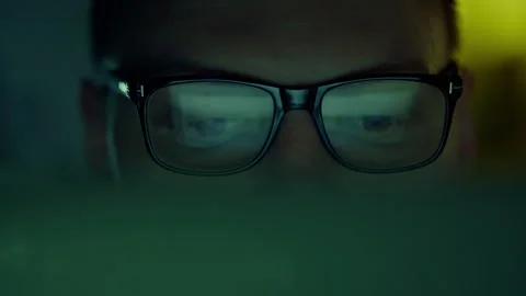 Close-up of a man's eyes, an IT programmer, a man with glasses, peers at the Stock Footage 256164561
