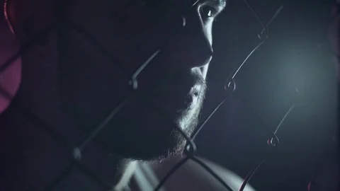 Close-up of a man's face behind a mesh. It's a dark room. Stock Footage 80862203